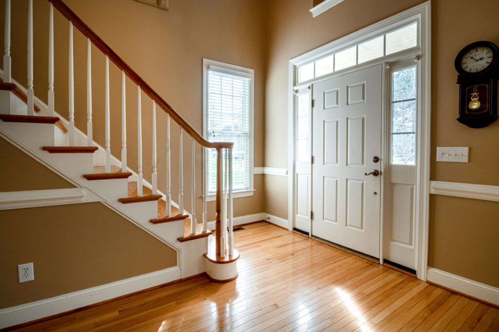 front-door-facing-stairs A front door directly facing a staircase inside a traditional home with wooden flooring.