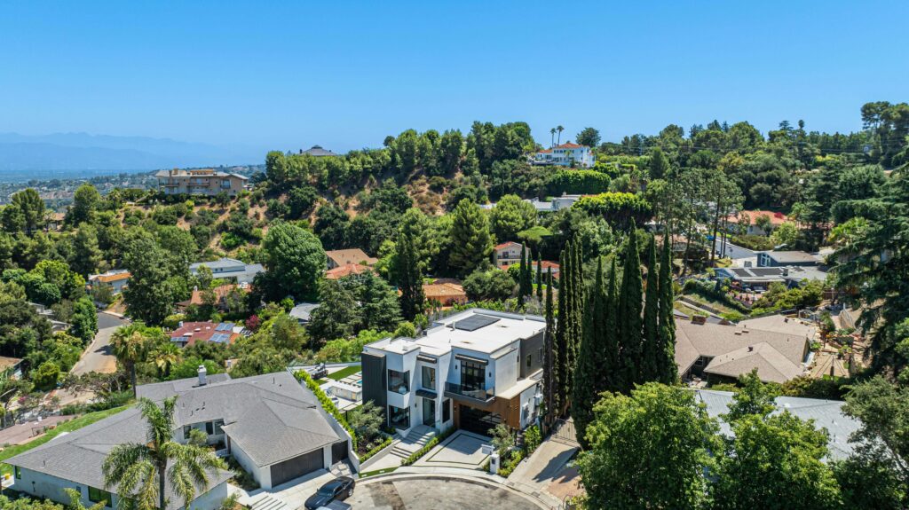 southern-california-hillside-homes Aerial photograph of hillside residential neighborhood in Los Angeles, with modern homes built against wooded slopes and hills in the background.