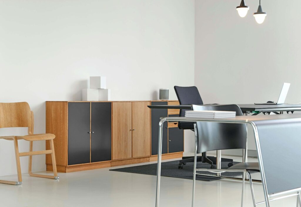 Home office desk facing the room with solid wall backing and a mid-high back chair, side window light, feng shui command position