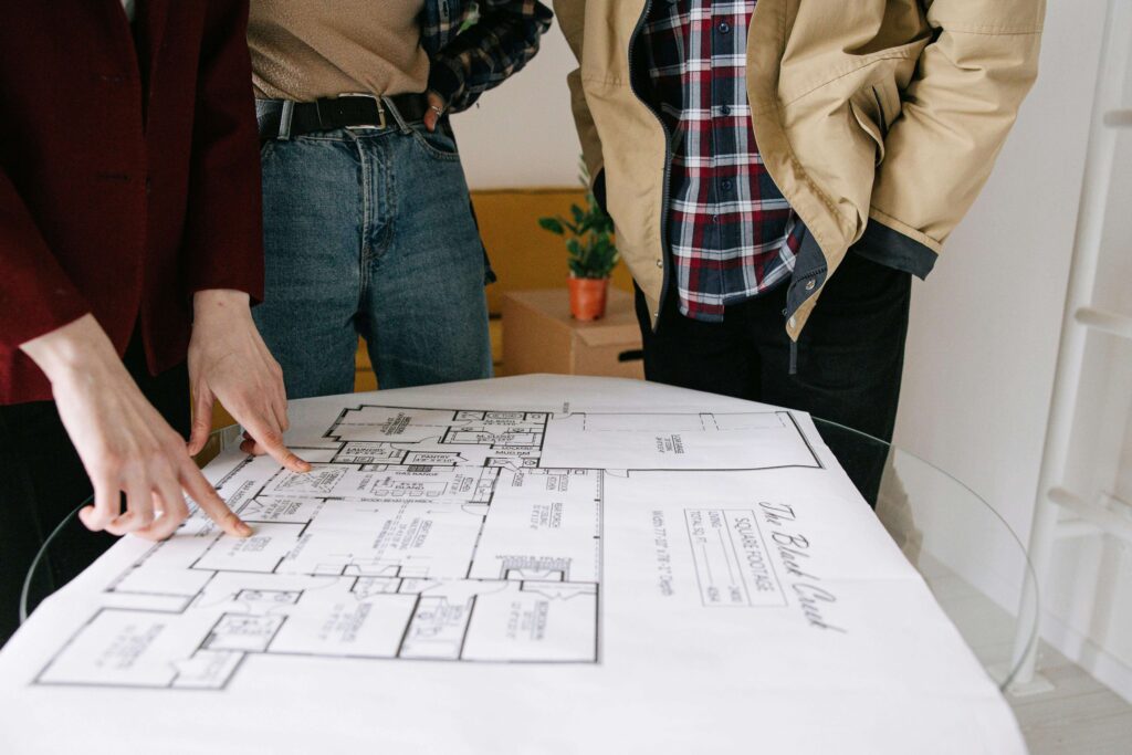 Hands pointing to a home floor plan during a layout review, discussing home office placement