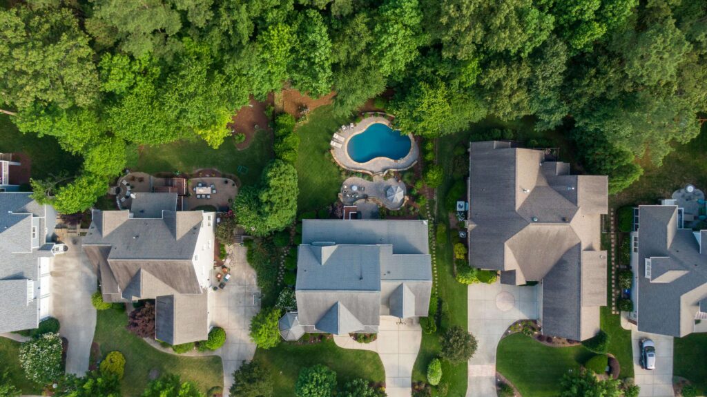 Aerial view of suburban homes with a backyard pool that balances well with the house and garden, illustrating Feng Shui guidelines for pool size and proportion.