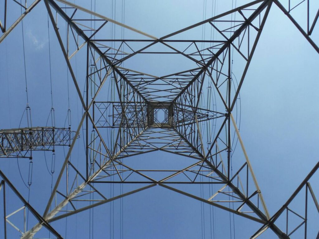 Upward view of a high-voltage power pylon against the sky, creating visual pressure in Feng Shui.