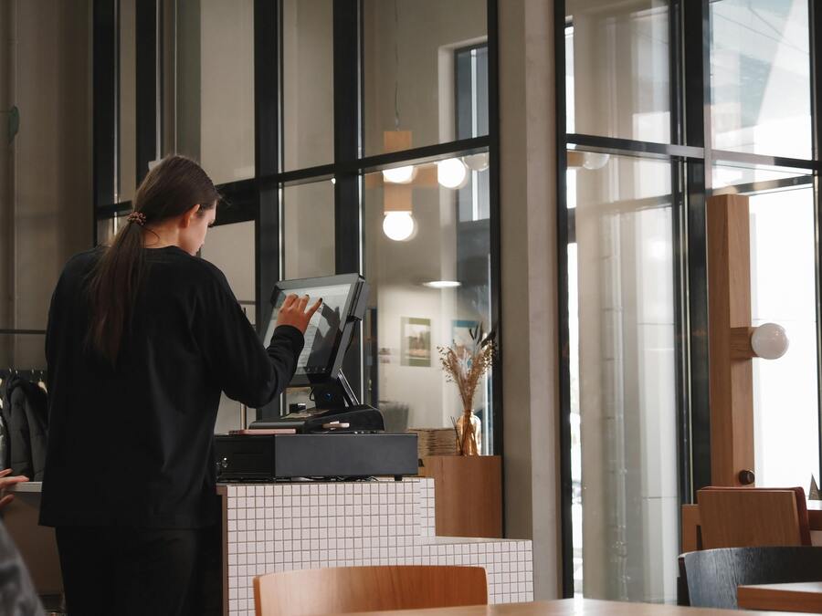 Restaurant cashier working at the register in a bright modern space, symbolizing financial stability and command position
